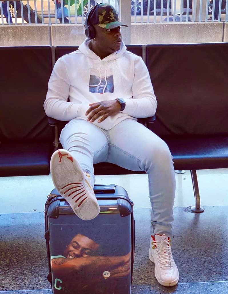 Kirk Jay in headphones at the airport with a suitcase